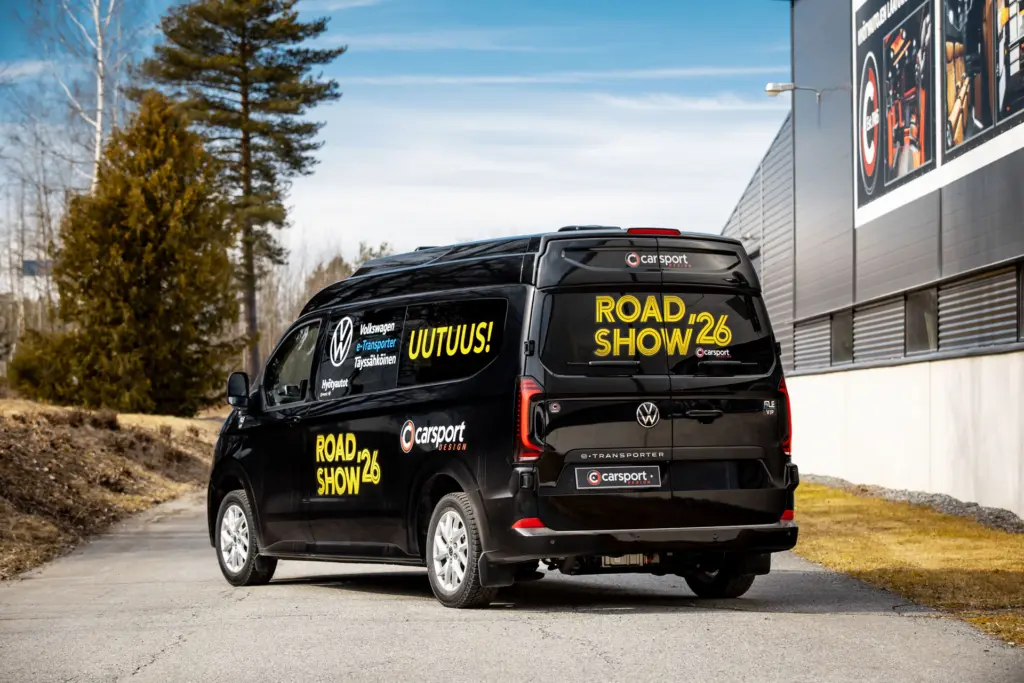 Musta korotettu eTansporter johon teipattu näyttävät Road Show ´26 teippaukset.